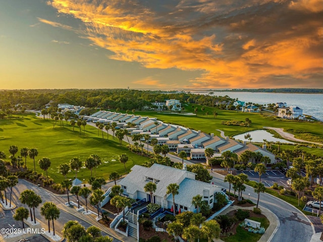 aerial view at dusk with a water view and golf course view