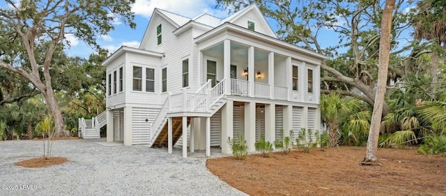 coastal home with a porch, metal roof, and stairs