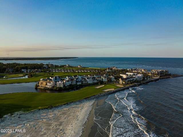 aerial view at dusk featuring a water view and a view of the beach