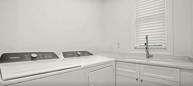 clothes washing area with washer and dryer, cabinet space, and a sink