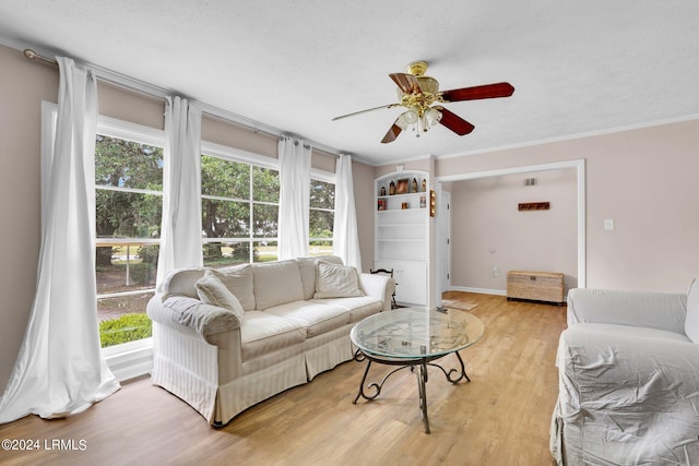 living room featuring ceiling fan, ornamental molding, light hardwood / wood-style floors, and a textured ceiling