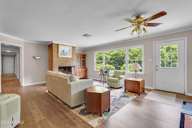 living room with crown molding, hardwood / wood-style flooring, a fireplace, and ceiling fan