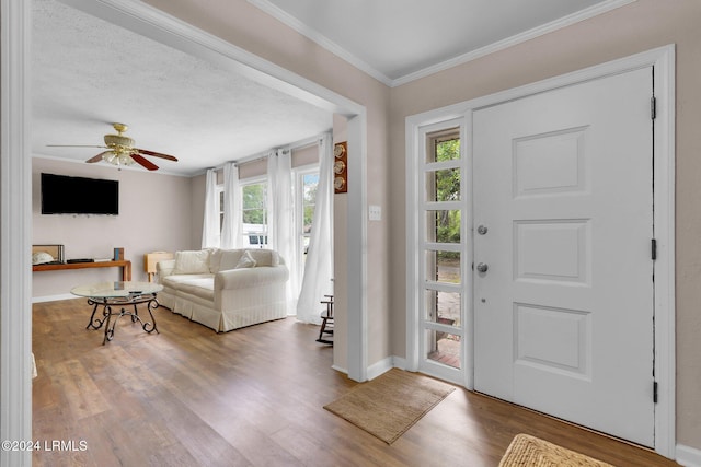 entryway with hardwood / wood-style flooring, ceiling fan, ornamental molding, and a textured ceiling