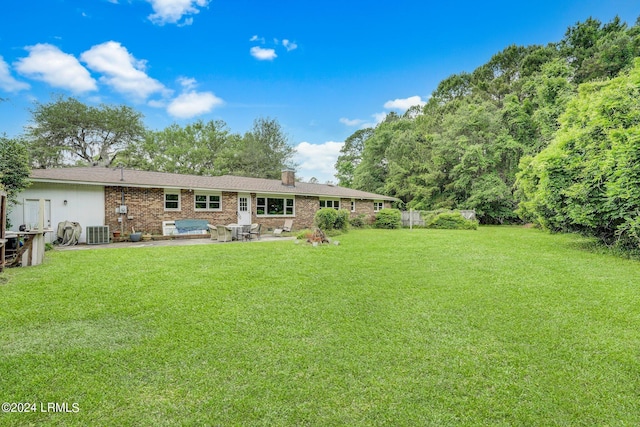 rear view of house with cooling unit, a patio area, and a lawn