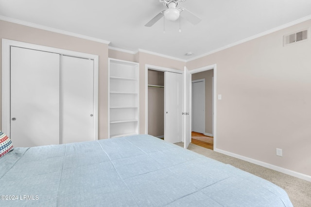 carpeted bedroom featuring multiple closets, ornamental molding, and ceiling fan