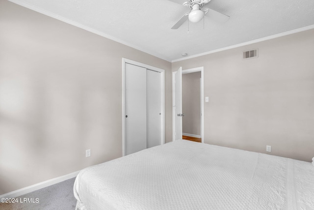 carpeted bedroom featuring ceiling fan, ornamental molding, and a closet