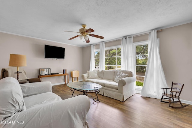 living room with hardwood / wood-style flooring, ceiling fan, ornamental molding, and a textured ceiling