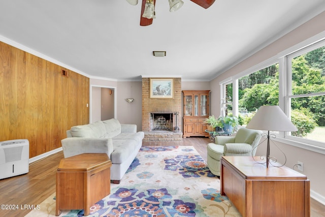 living room with crown molding, a brick fireplace, a wealth of natural light, and light wood-type flooring