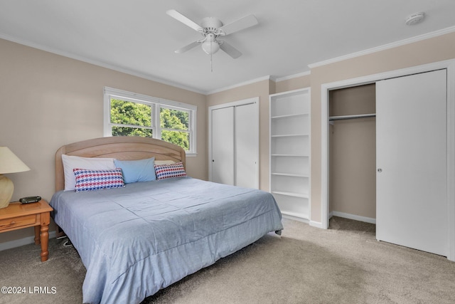 bedroom featuring crown molding, ceiling fan, light carpet, and two closets