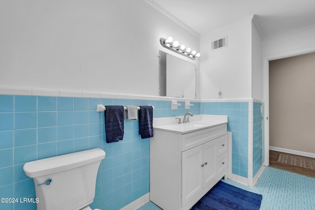 bathroom with crown molding, tile walls, vanity, tile patterned floors, and toilet