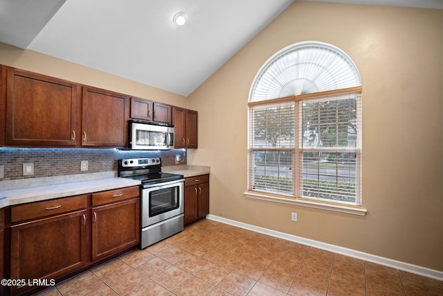 kitchen featuring appliances with stainless steel finishes, light countertops, vaulted ceiling, and tasteful backsplash