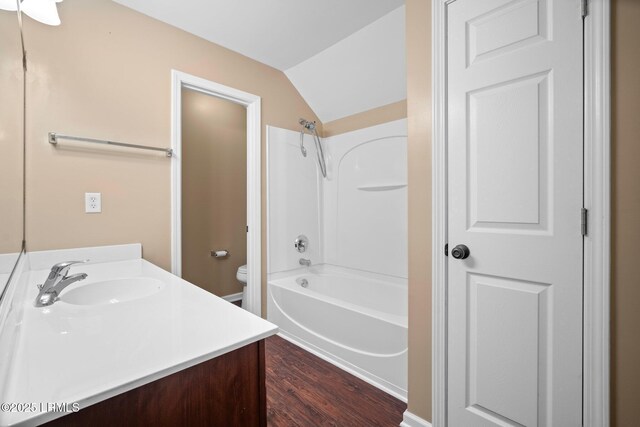 bathroom with toilet, shower / tub combination, wood finished floors, vaulted ceiling, and vanity