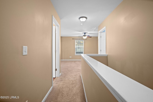 hall featuring baseboards, light carpet, and an upstairs landing