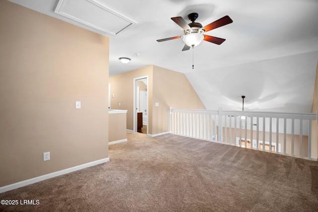 carpeted spare room featuring baseboards, vaulted ceiling, and a ceiling fan