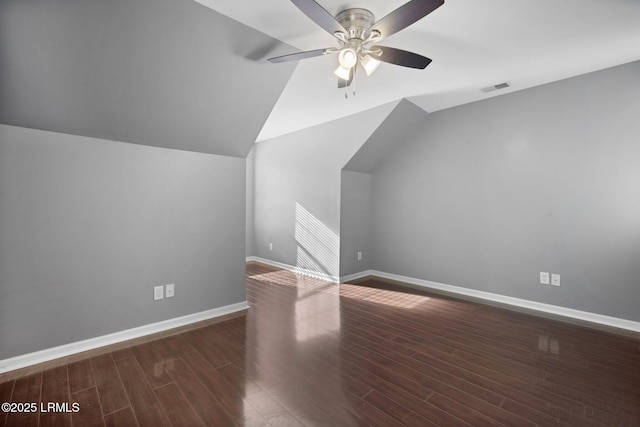 additional living space with lofted ceiling, dark wood-style flooring, visible vents, and baseboards