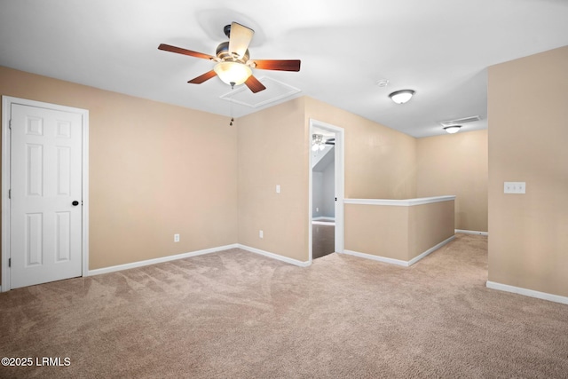 unfurnished room featuring attic access, light carpet, baseboards, and a ceiling fan