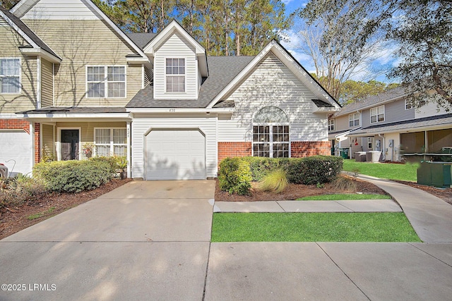 traditional-style house with concrete driveway, brick siding, an attached garage, and central air condition unit