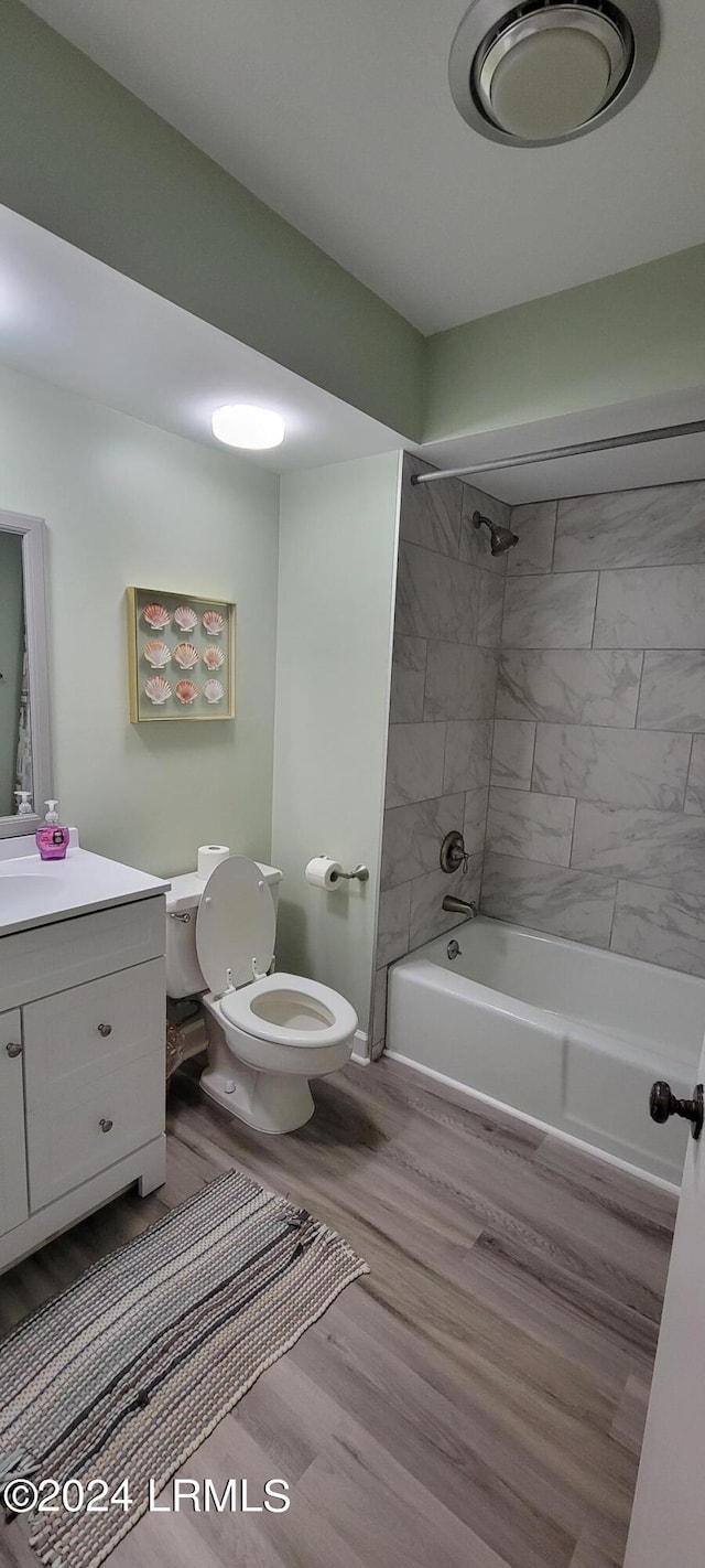 full bathroom featuring vanity, hardwood / wood-style flooring, toilet, and tiled shower / bath