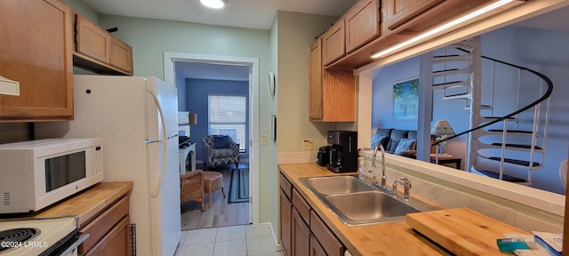 kitchen featuring electric range, butcher block counters, sink, and light tile patterned floors