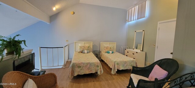 bedroom featuring vaulted ceiling, a textured ceiling, and light hardwood / wood-style flooring