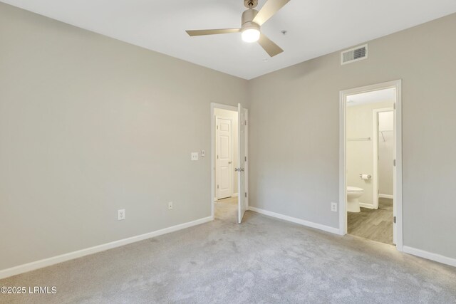 unfurnished bedroom featuring ensuite bathroom, a spacious closet, ceiling fan, light carpet, and a closet