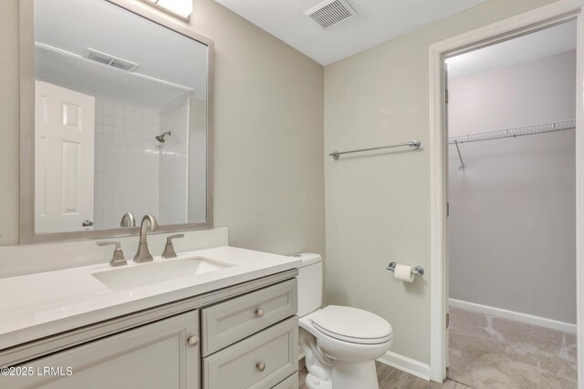 bathroom featuring tiled shower, vanity, and toilet