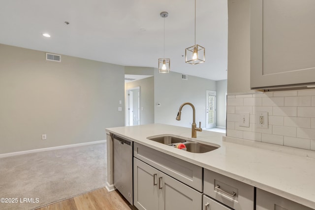 kitchen featuring gray cabinets, pendant lighting, dishwasher, sink, and light stone counters