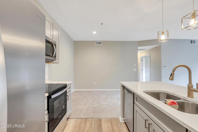 kitchen with sink, decorative light fixtures, stainless steel appliances, and light hardwood / wood-style floors