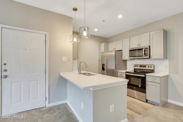 kitchen with appliances with stainless steel finishes, decorative light fixtures, tasteful backsplash, sink, and kitchen peninsula