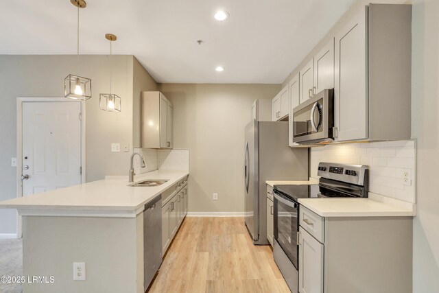 kitchen featuring pendant lighting, sink, appliances with stainless steel finishes, tasteful backsplash, and kitchen peninsula