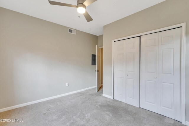 unfurnished bedroom with light colored carpet, a closet, ceiling fan, and electric panel