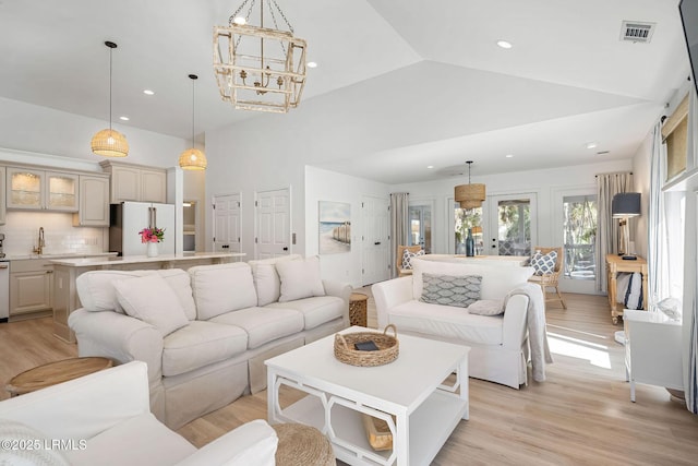 living room with high vaulted ceiling, light wood-type flooring, visible vents, and recessed lighting