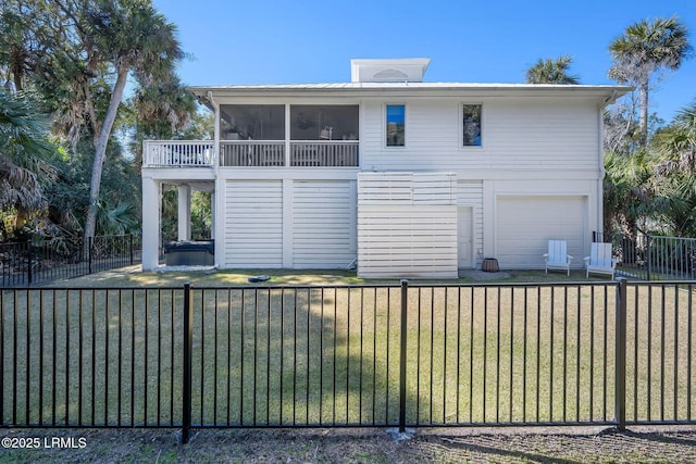 rear view of property featuring a garage, a lawn, fence, and a sunroom