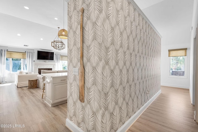 corridor with light wood finished floors, an accent wall, baseboards, and recessed lighting