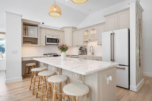 kitchen with white appliances, light wood finished floors, a center island, a sink, and backsplash