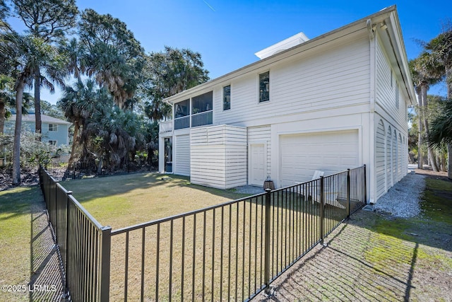 exterior space with an attached garage, a fenced backyard, and a yard