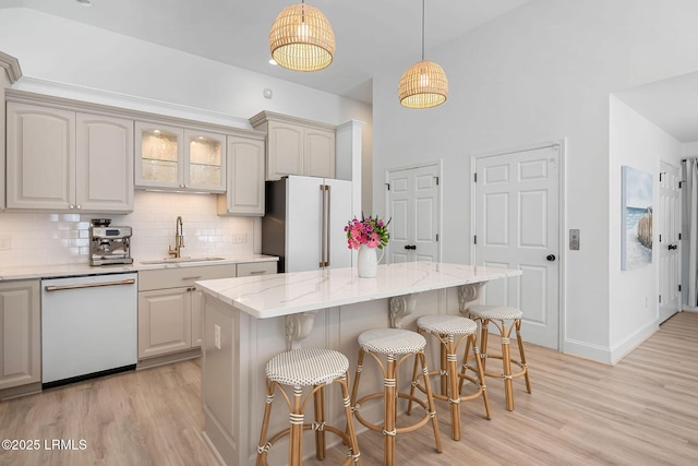 kitchen with white appliances, a breakfast bar, a sink, light wood-style floors, and backsplash