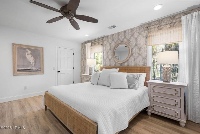 bedroom with wallpapered walls, baseboards, visible vents, light wood-type flooring, and multiple windows