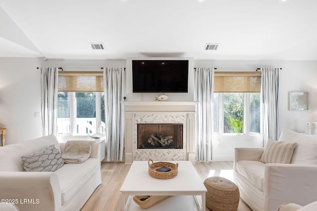 living area featuring a wealth of natural light, visible vents, and light wood-style floors