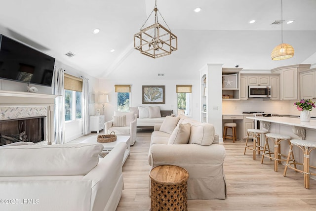 living area featuring light wood finished floors, recessed lighting, visible vents, high vaulted ceiling, and a tile fireplace