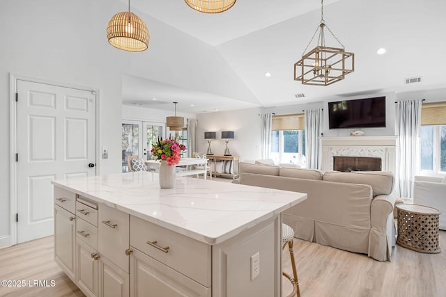 kitchen with light wood-type flooring, lofted ceiling, visible vents, and a kitchen island