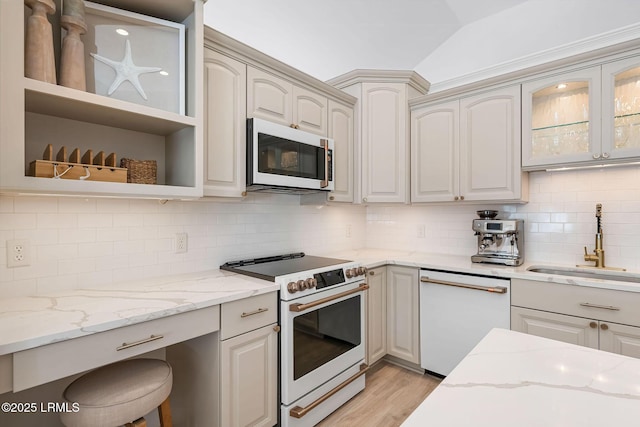 kitchen featuring light stone counters, open shelves, vaulted ceiling, a sink, and white appliances