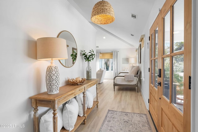 interior space featuring lofted ceiling, light wood finished floors, a healthy amount of sunlight, and visible vents