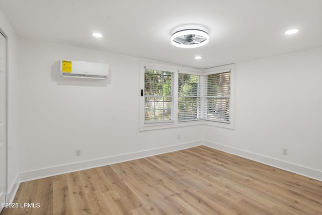 unfurnished room with a wall unit AC and light hardwood / wood-style floors