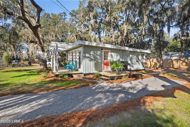 view of front of house featuring an outbuilding, a deck, and a front yard