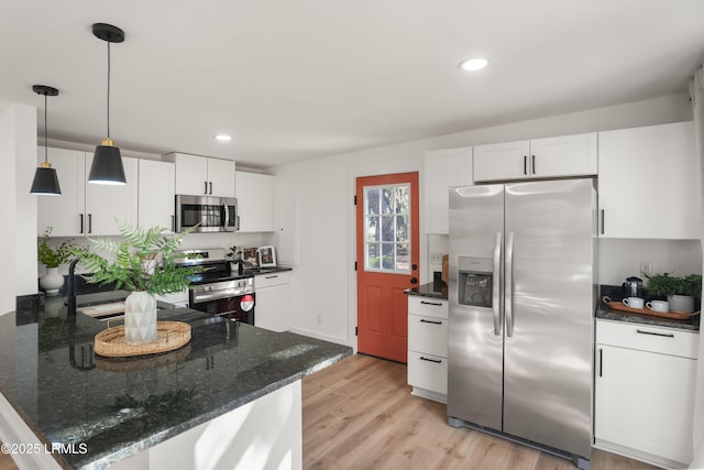 kitchen featuring white cabinetry, hanging light fixtures, light wood-type flooring, dark stone countertops, and stainless steel appliances