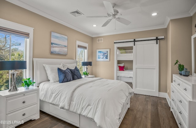 bedroom with dark wood-style floors, a barn door, visible vents, and crown molding