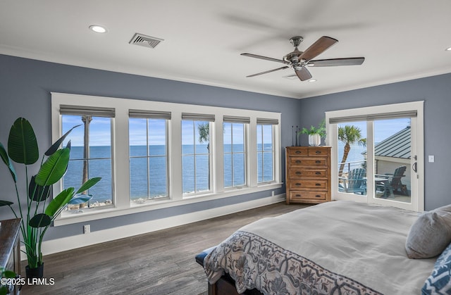 bedroom featuring dark wood-type flooring, a water view, visible vents, baseboards, and ornamental molding