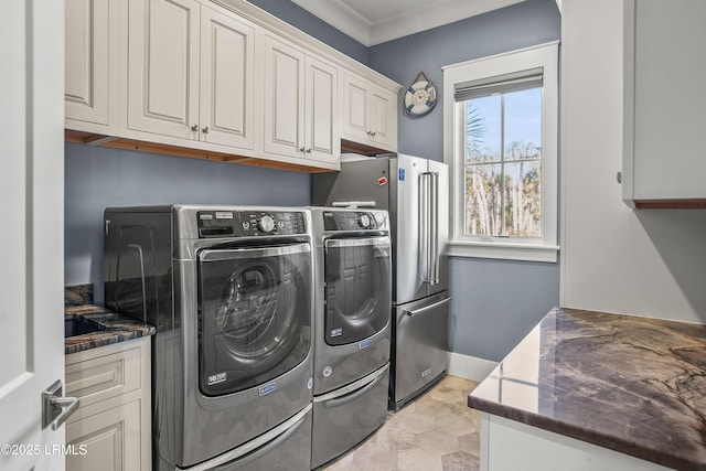 clothes washing area with baseboards, cabinet space, crown molding, and washing machine and clothes dryer