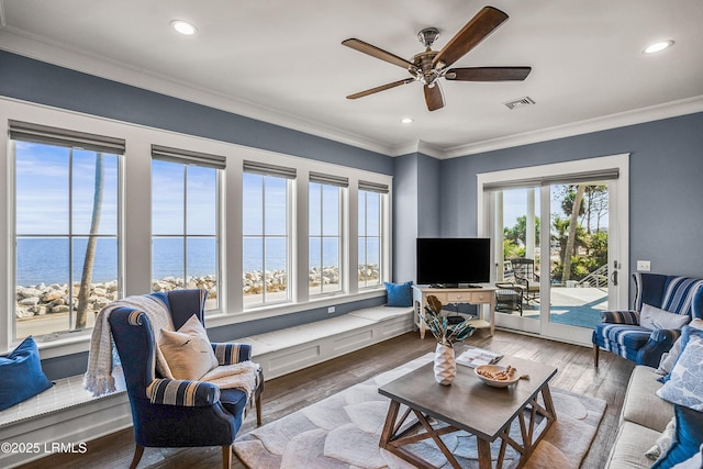 living room with ornamental molding, a water view, wood finished floors, and visible vents